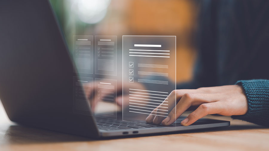 Abstract of typed pages with person behind typing on a laptop